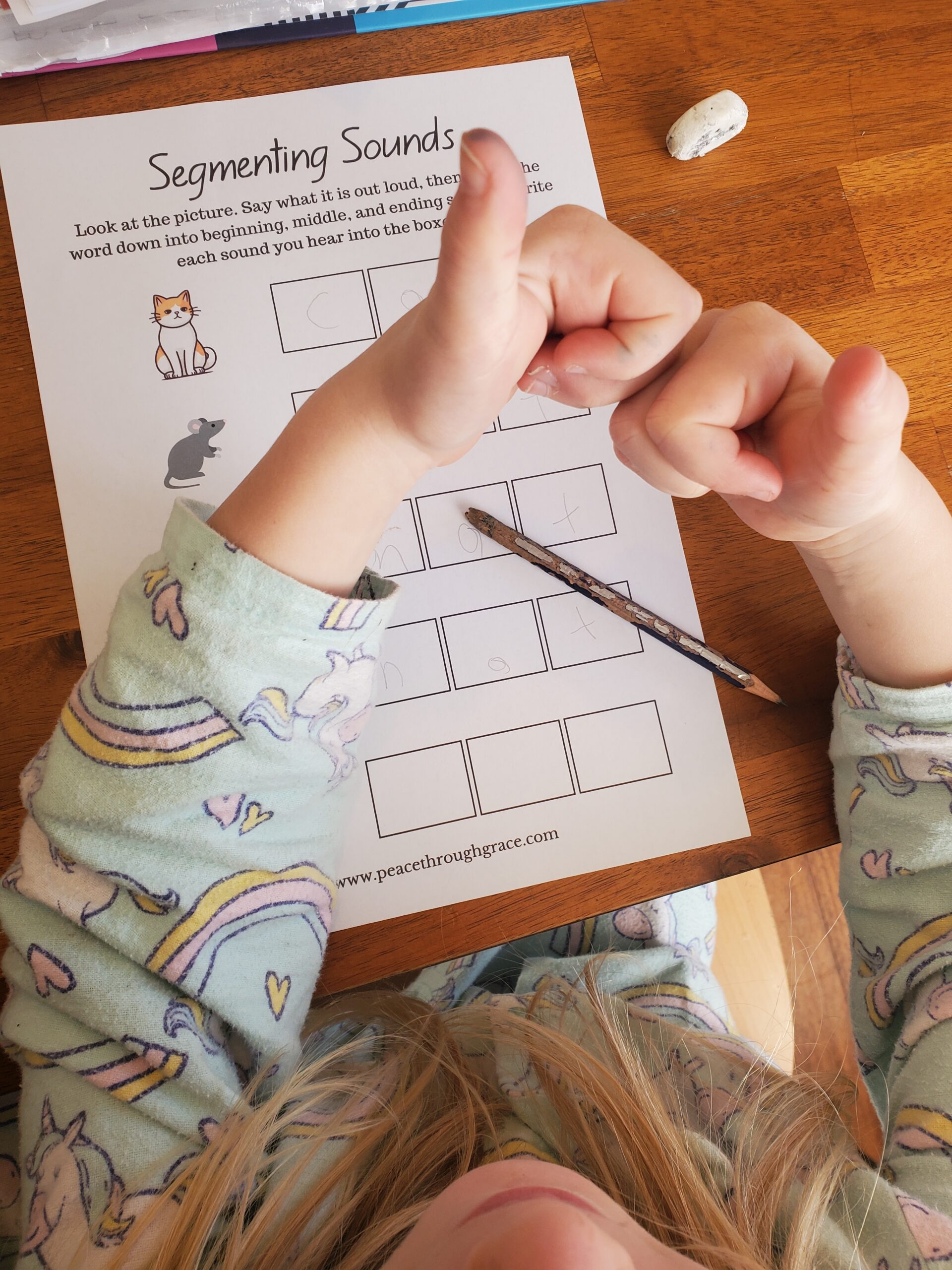 Child holding up thumbs so show how to spell "bed" with phonics tricks